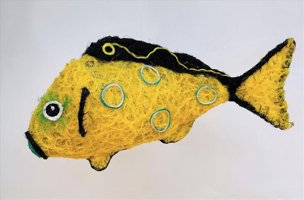 Sculpture of a yellow and black fish with blue and yellow detail, made out of reclaimed fishing nets