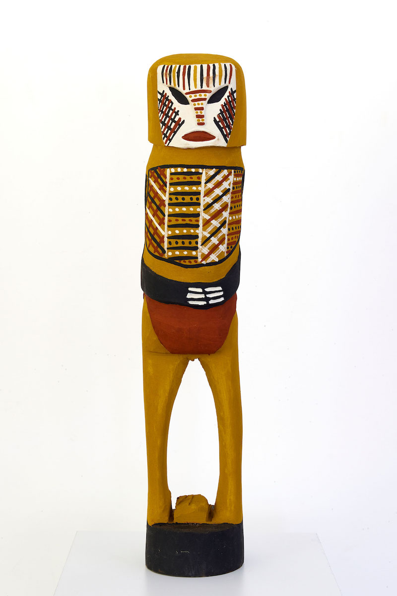 Carved figurative sculpture with painted markings in black, red, yellow ochre and white.