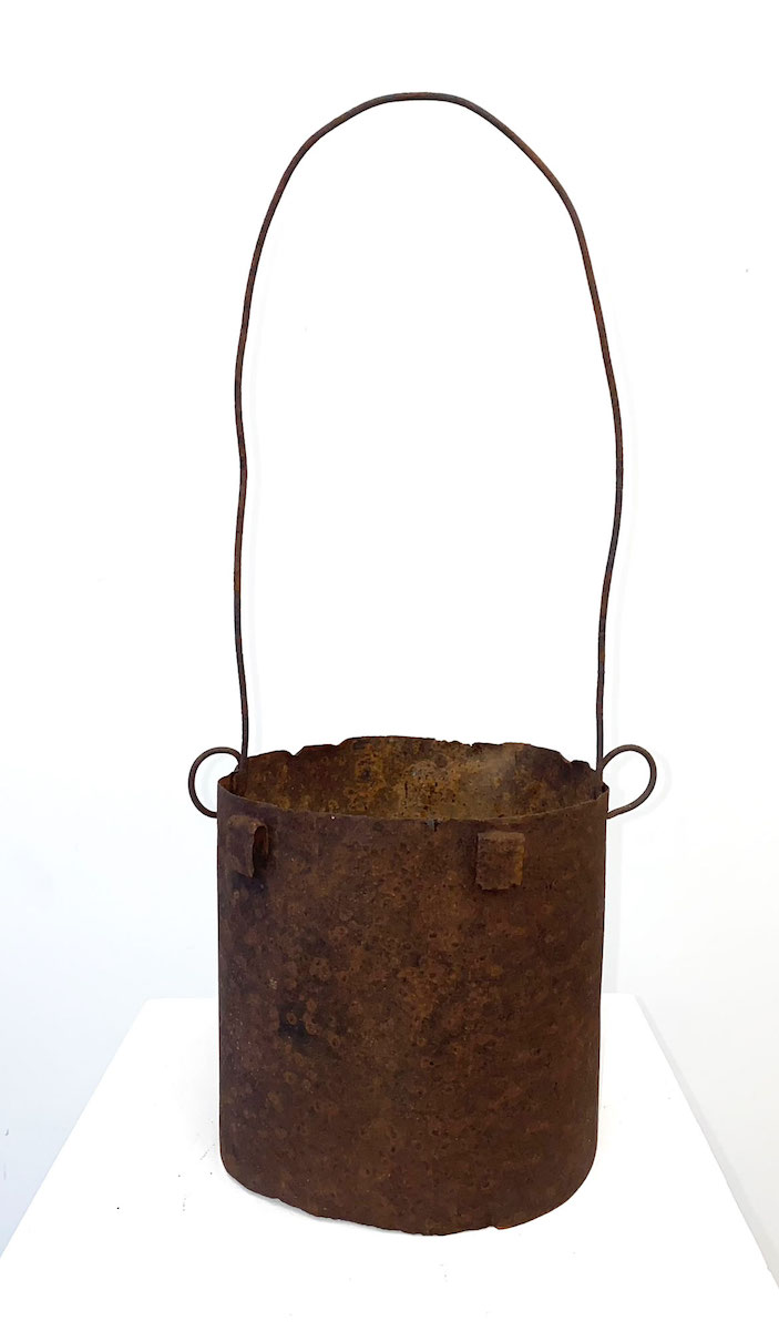 A bag-shaped sculpture made of rusted tin and fencing wire