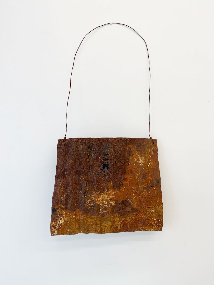 A large bag-shaped sculpture made of rusted wire and corrugated iron