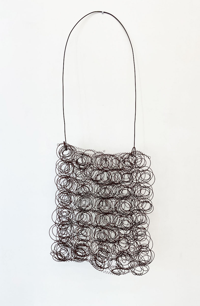 A large bag-shaped sculpture made of rusted bed springs and fencing wire