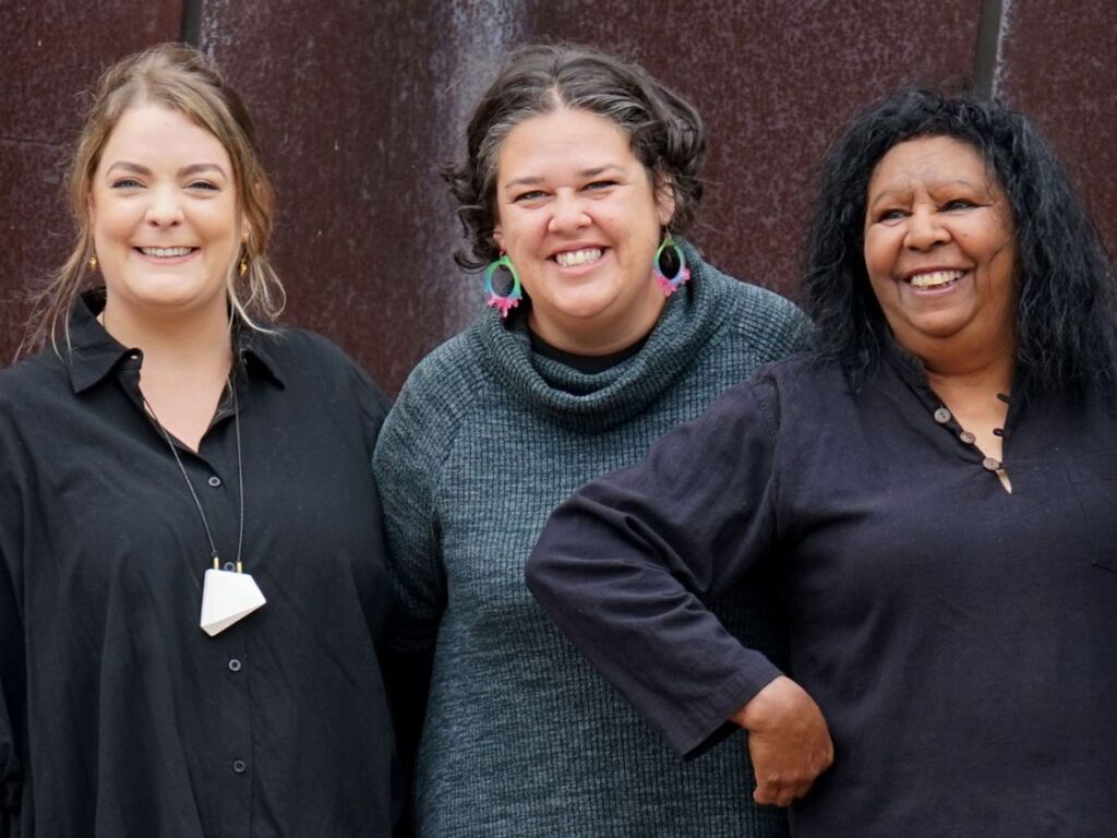 Image of three women wearing black and smiling.