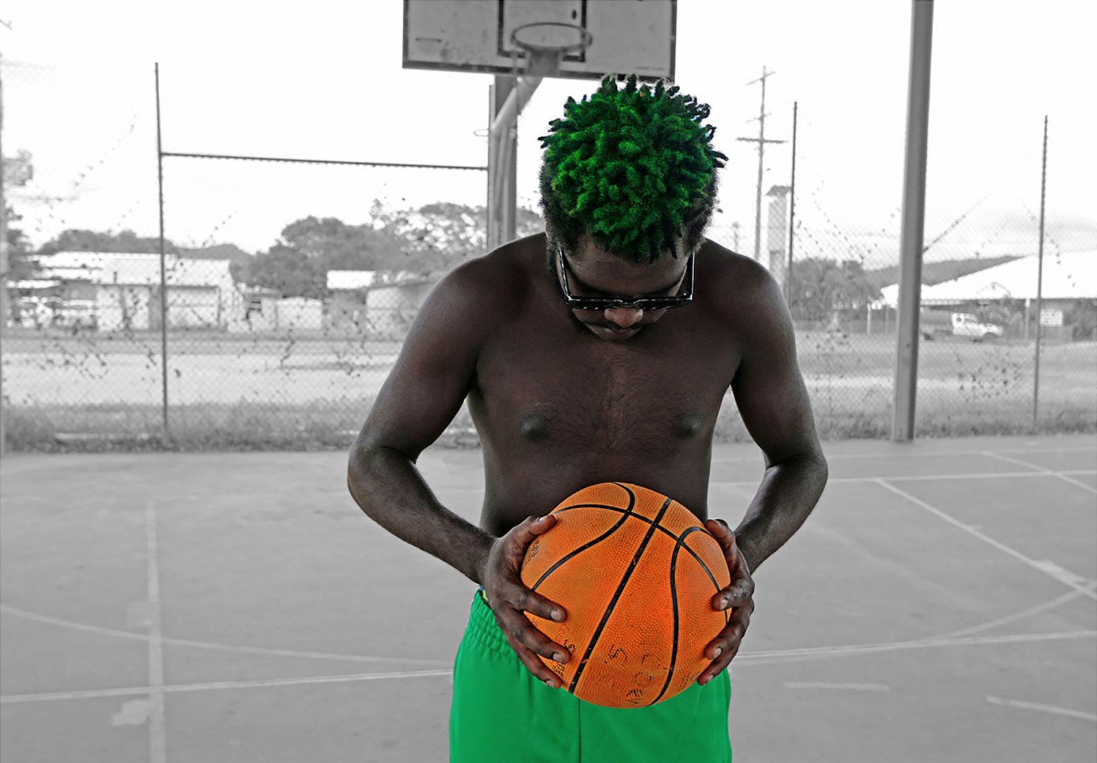 Young person looking down, holding a basketball on the court.